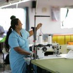 She threads a sowing machine to get it ready to make more sails.