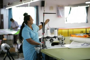 She threads a sowing machine to get it ready to make more sails.