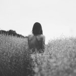 She walks away through the high grass.